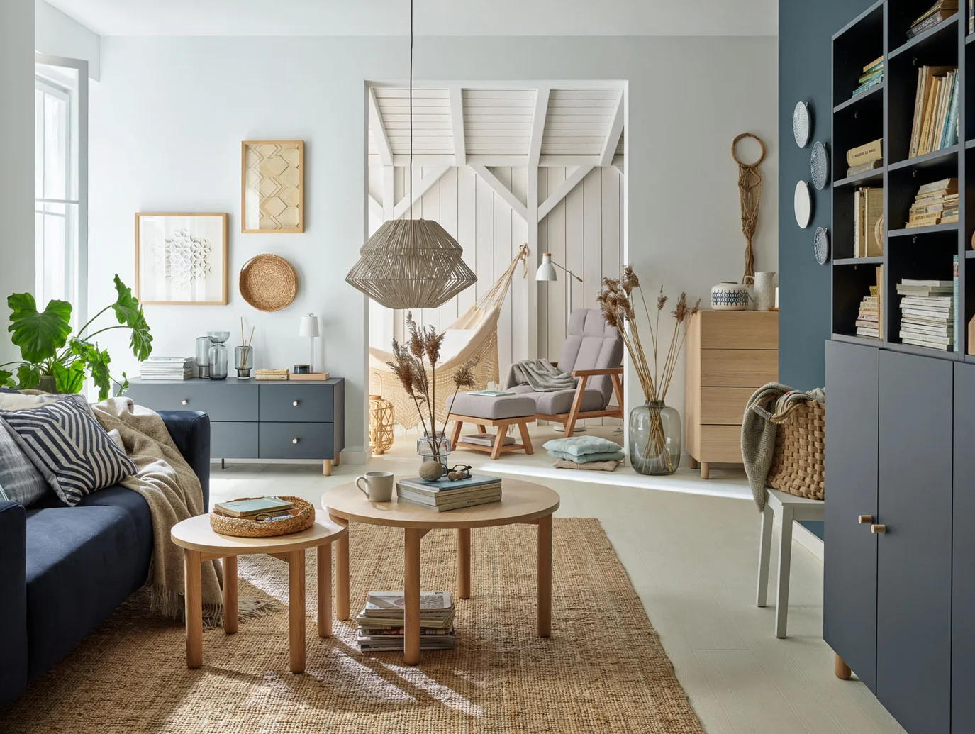Salon w stylu boho z granatową sofą, naturalnym dywanem z juty i meblami z jasnego drewna na tle jasnych ścian